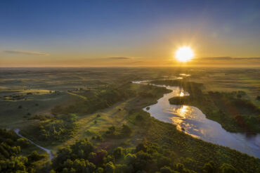 sunrise over Dismal River meandering through Nebraska Sandhills at Nebraska National Forest, aerial view of summer scenery
