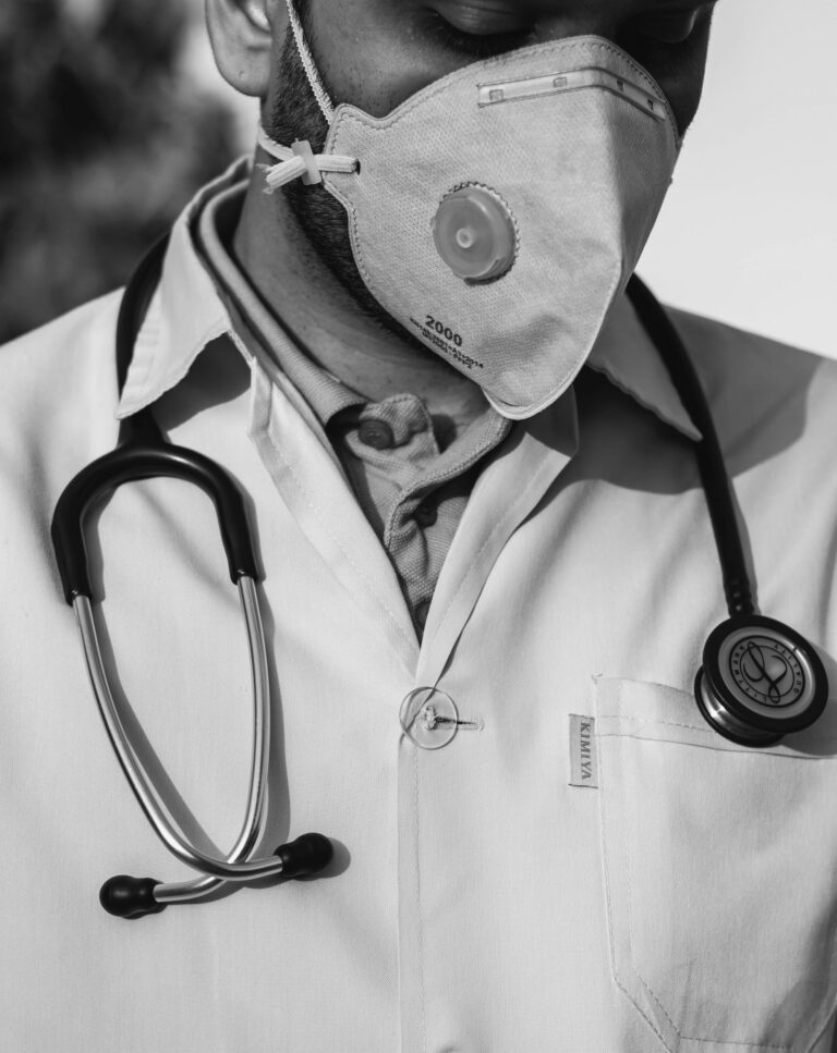 black and white image of a male physician wearing stethoscope and face mask