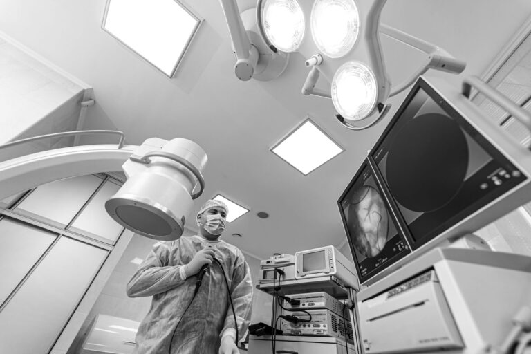 male physician in surgical gown looking at xray on monitor