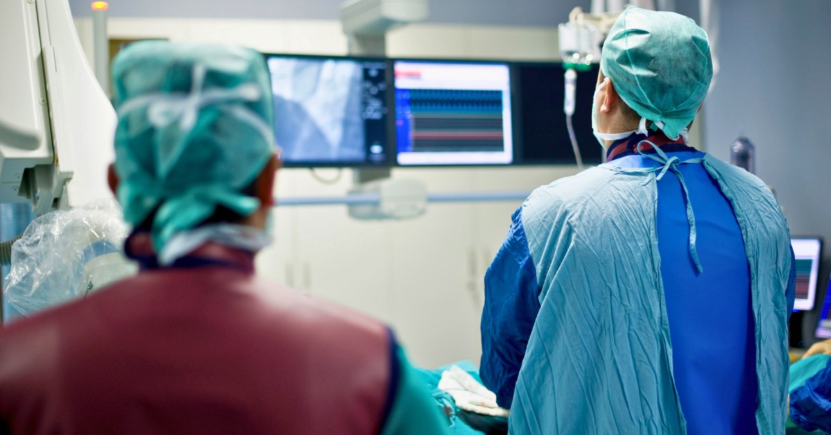 view of two cardiologists from behind inside a cath lab