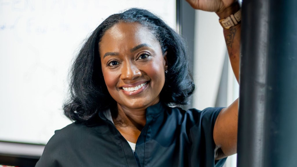 Anesthesiologist Dr. LaKesha Legree in dark scrubs and leaning against a wall while smiling