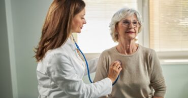 Healthcare professional using a stethoscope during a patient exam, representing sustainable cardiology programs that support consistent, high-quality cardiovascular care.