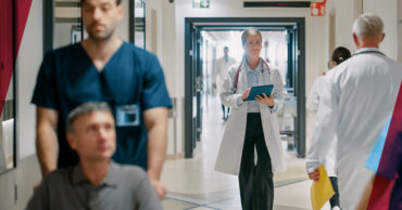 women in white lab coat walking down a hallway